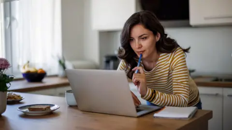 Getty Images Woman sitting at laptop in a stripy top - stock shot