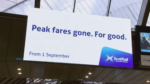 A digital billboard at Queen Street Station in Glasgow says "Peak fares. Gone for good."