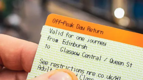 Getty Images A close-up image of a train ticket from Edinburgh to Glasgow Central, held in someone's hand. The ticket is orange and white.