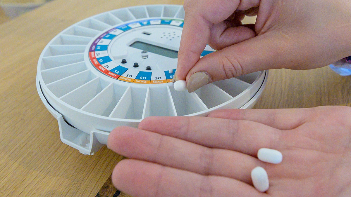 A person filling their pill dispenser.